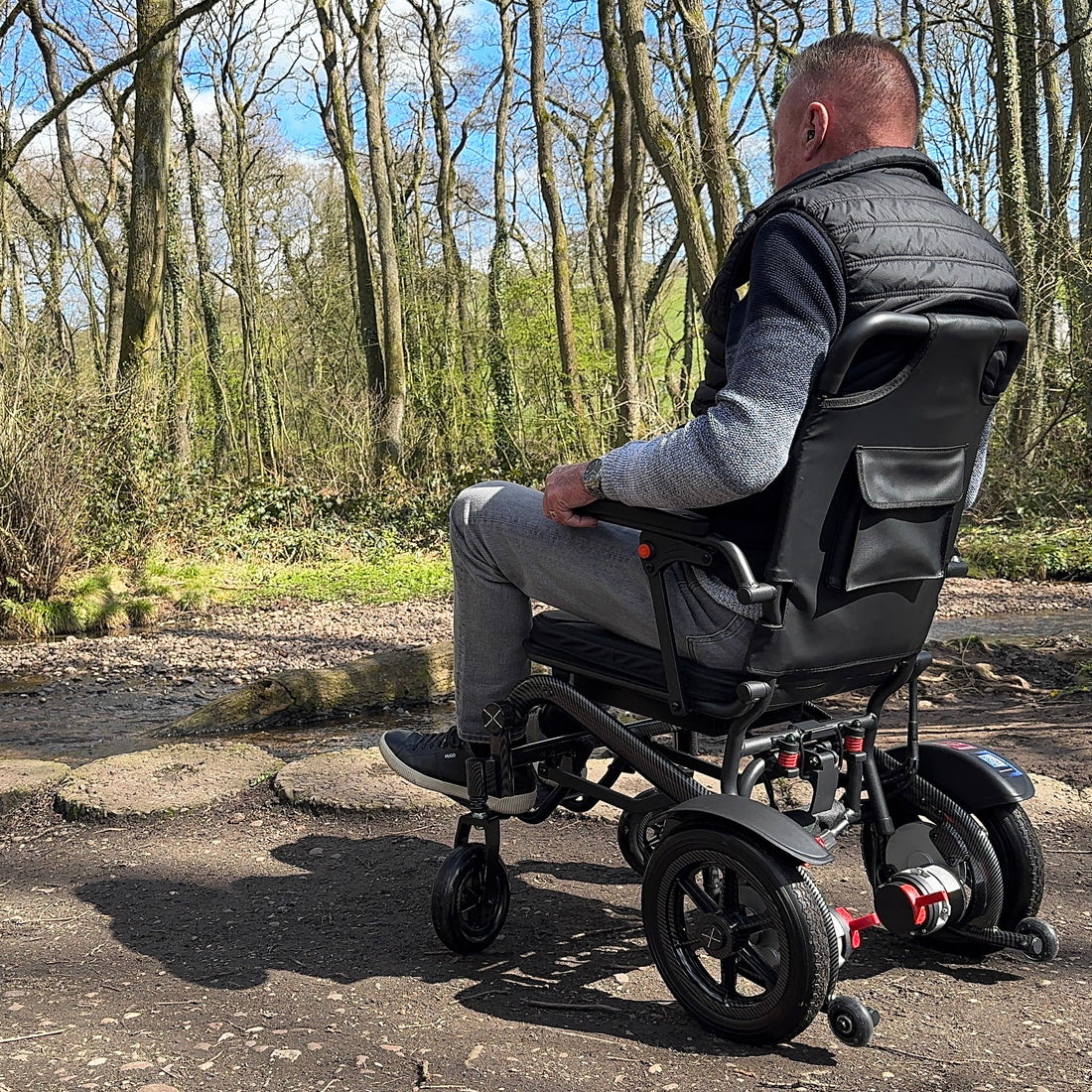 Man in a power wheelchair in a forested area
