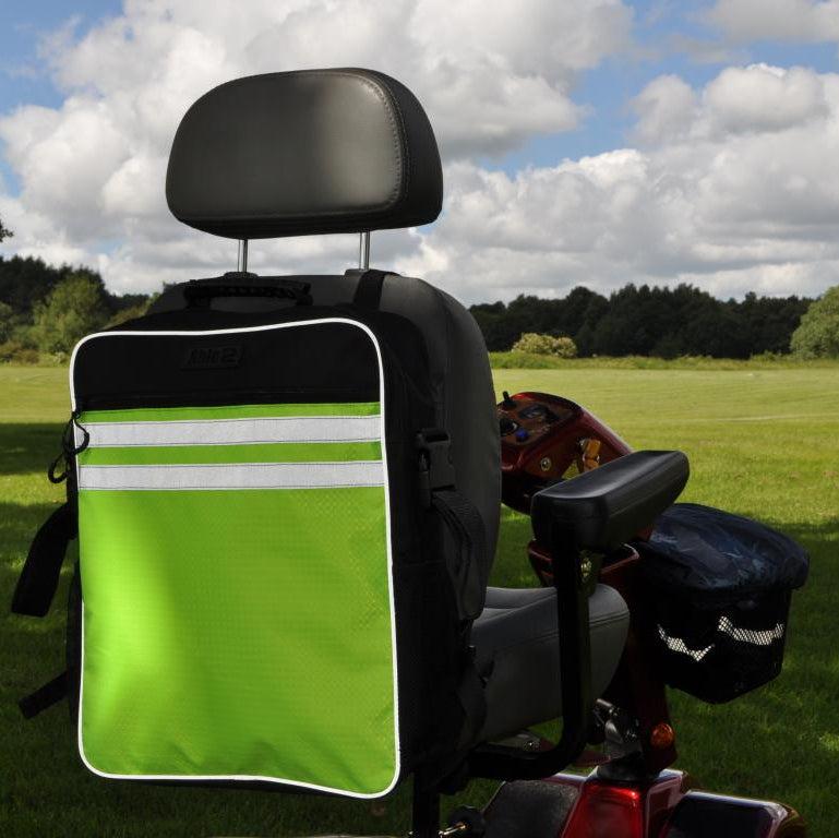 A green and black splash scooter bag attached to the back of a mobility scooter, set against an outdoor backdrop.